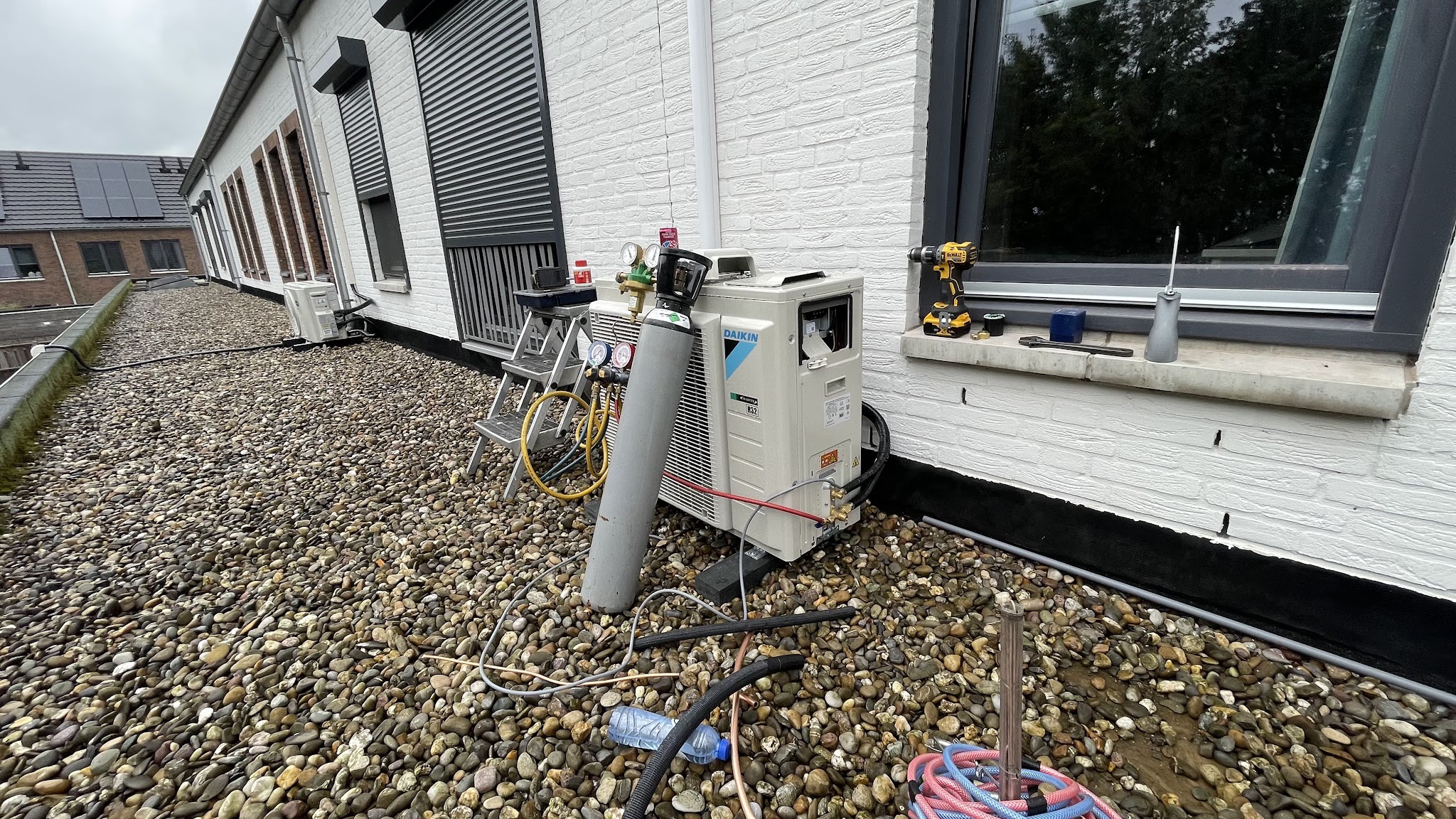 Installatie in uitvoering op een grinddak: buitenunit, stikstoffles, vacuümpomp en slangen