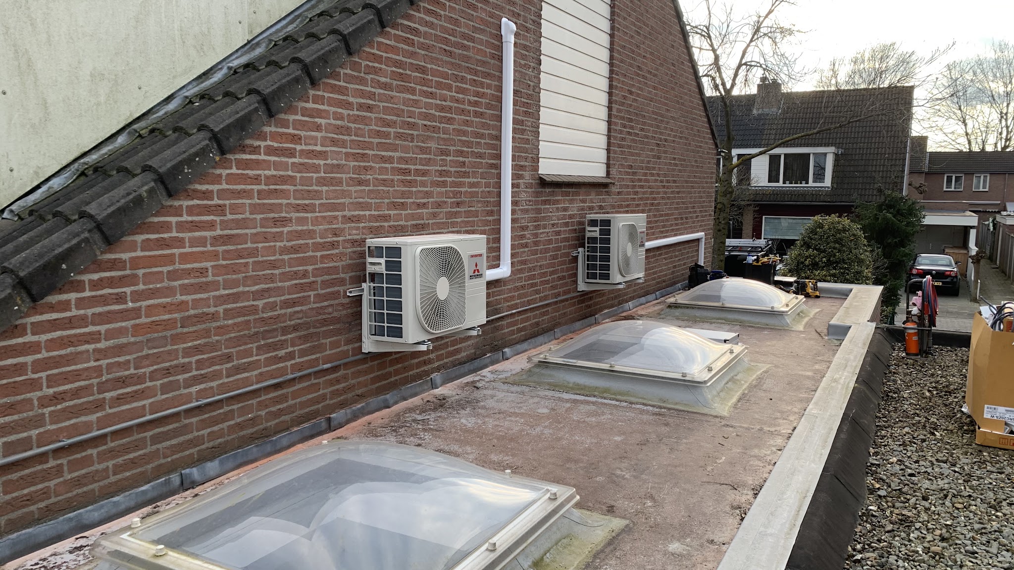 Twee buitenunits aan de gevel van een dakkapel, leidingen weggewerkt in witte goten
